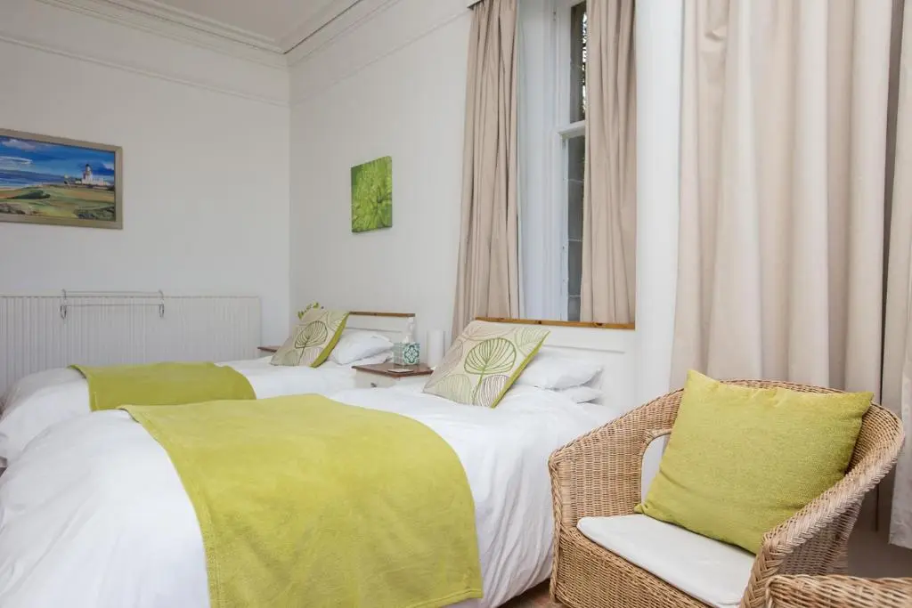 a bedroom with two beds and a chair and a window at Chrialdon House in Beauly