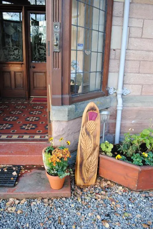 a wooden statue of a bird sitting outside of a building at Chrialdon House in Beauly