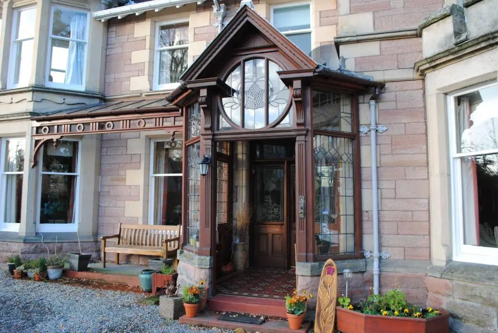 a building with a wooden door and a bench at Chrialdon House in Beauly