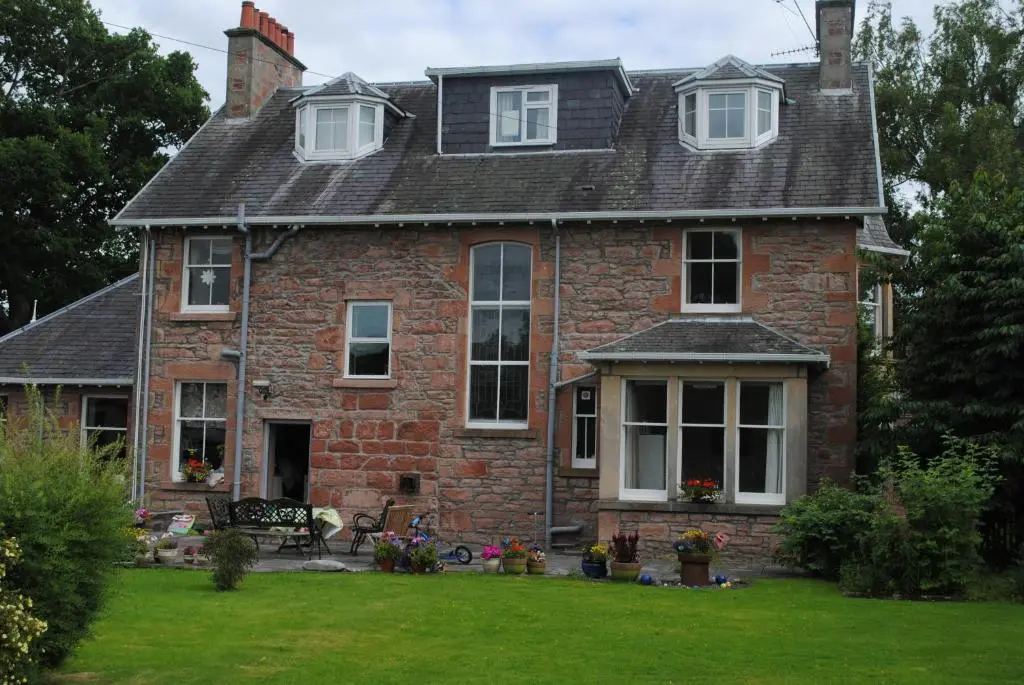 an old brick house with a lawn in front of it at Chrialdon House in Beauly