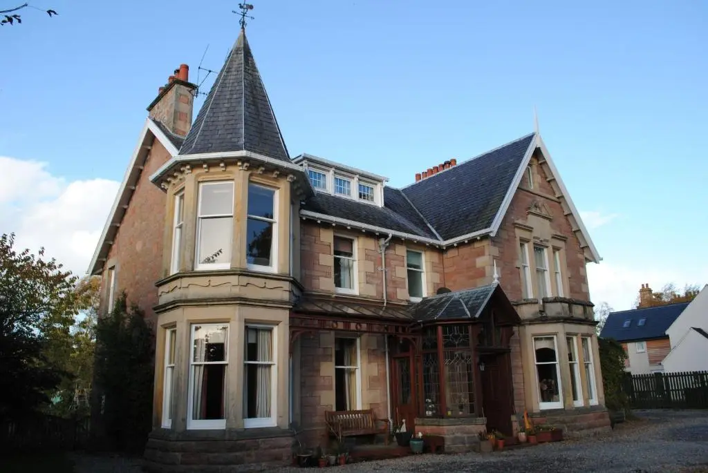 a large brick house with a pointed roof at Chrialdon House in Beauly