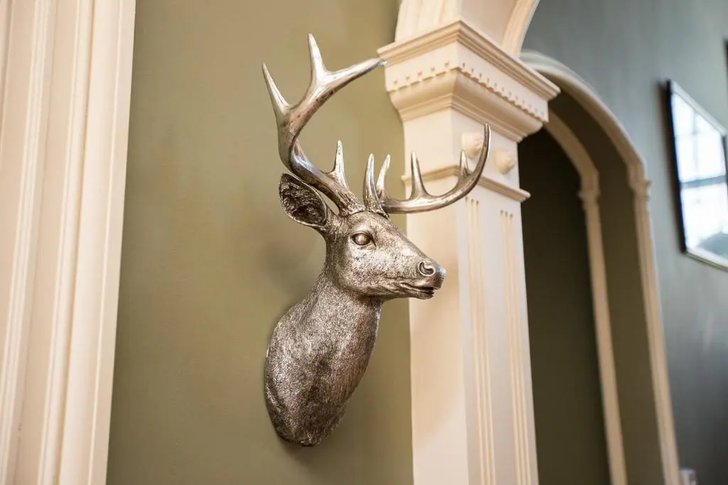 a statue of a deer hanging on a wall at Chrialdon House in Beauly