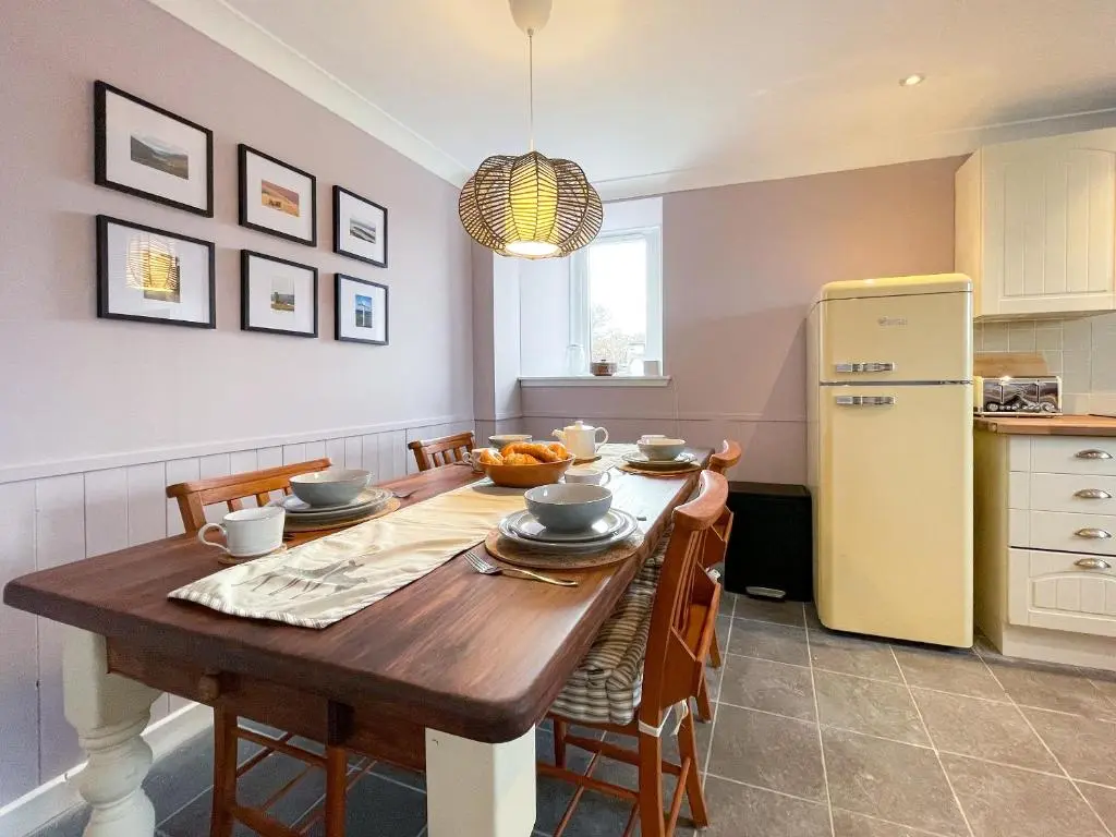 a kitchen with a wooden table and a refrigerator at The Grain Store in Aberarder