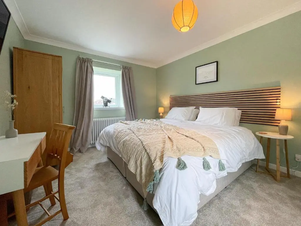 a bedroom with a bed and a desk and a window at The Grain Store in Aberarder