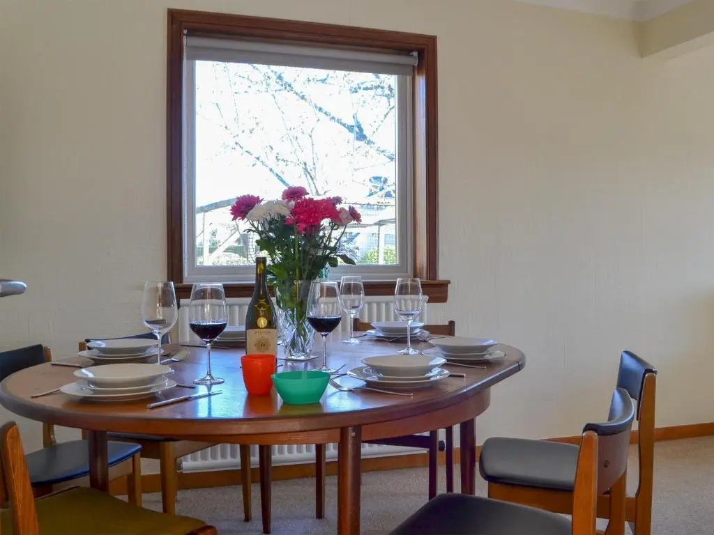 a dining room table with glasses and a vase of flowers at Wester Links in Fortrose