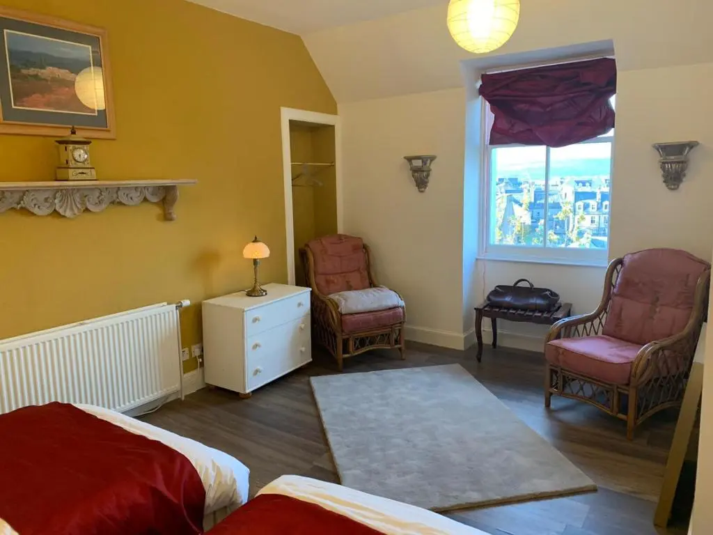 a bedroom with a bed and two chairs and a window at Hill House - Mews Town House, in a quiet private close, in the City Centre of Inverness. in Inverness