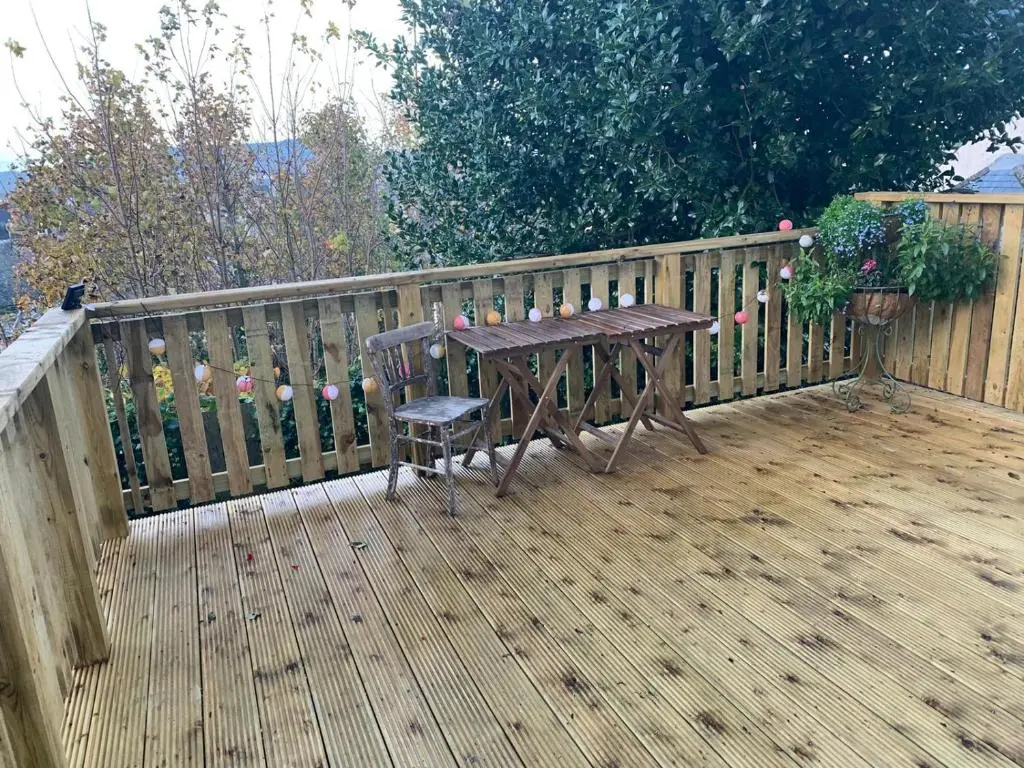 a wooden deck with a wooden table and a wooden fence at Hill House - Mews Town House, in a quiet private close, in the City Centre of Inverness. in Inverness