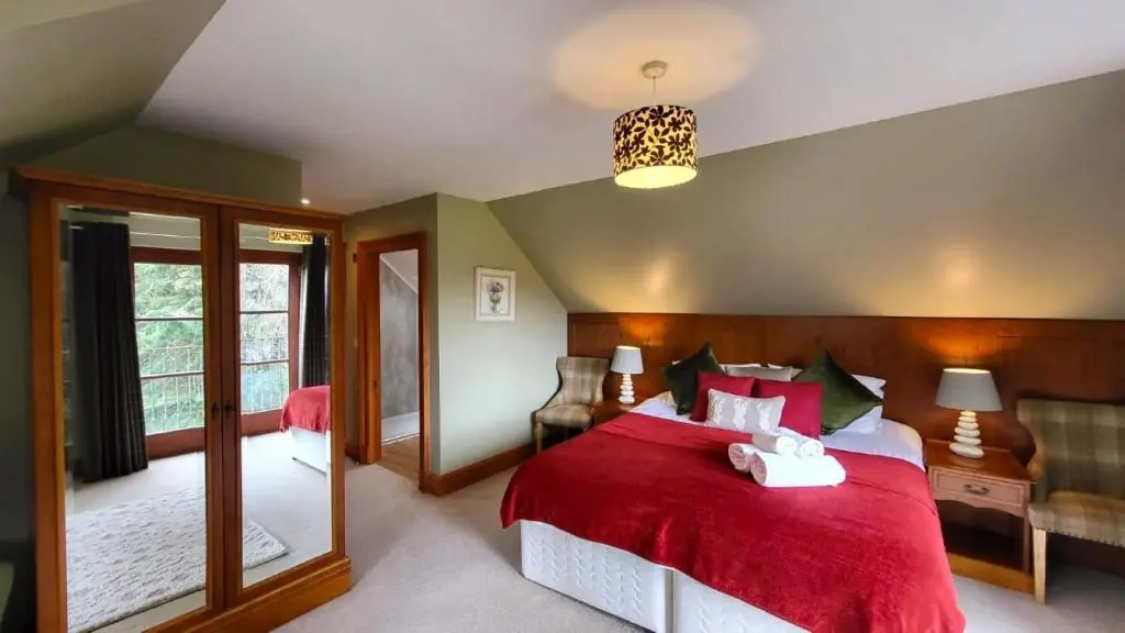 a bedroom with a red bed with a red blanket at Red Squirrel Lodge in Boat of Garten