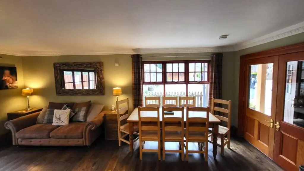 a living room with a table and a couch at Red Squirrel Lodge in Boat of Garten