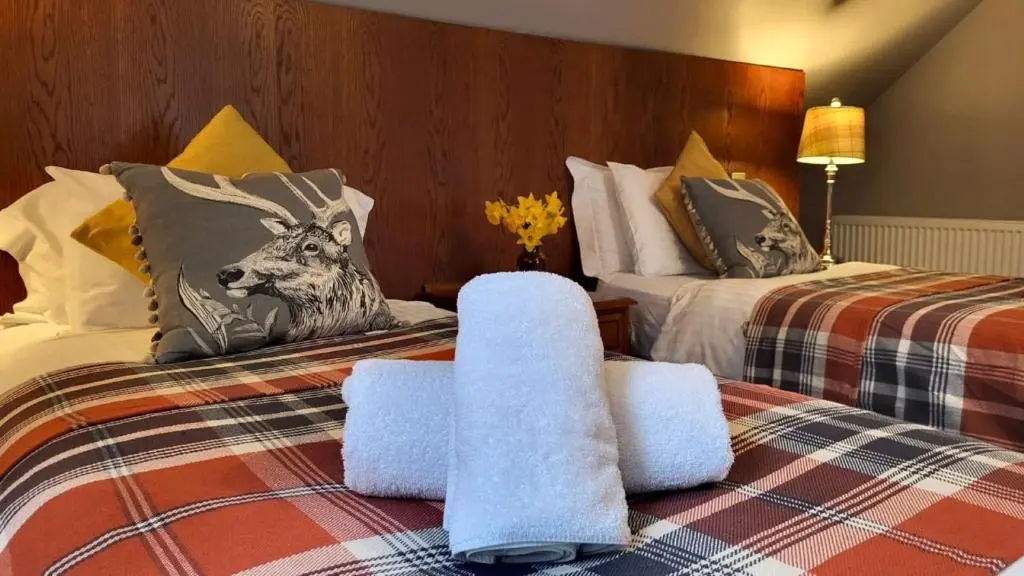 a bedroom with two beds with towels on them at Red Squirrel Lodge in Boat of Garten