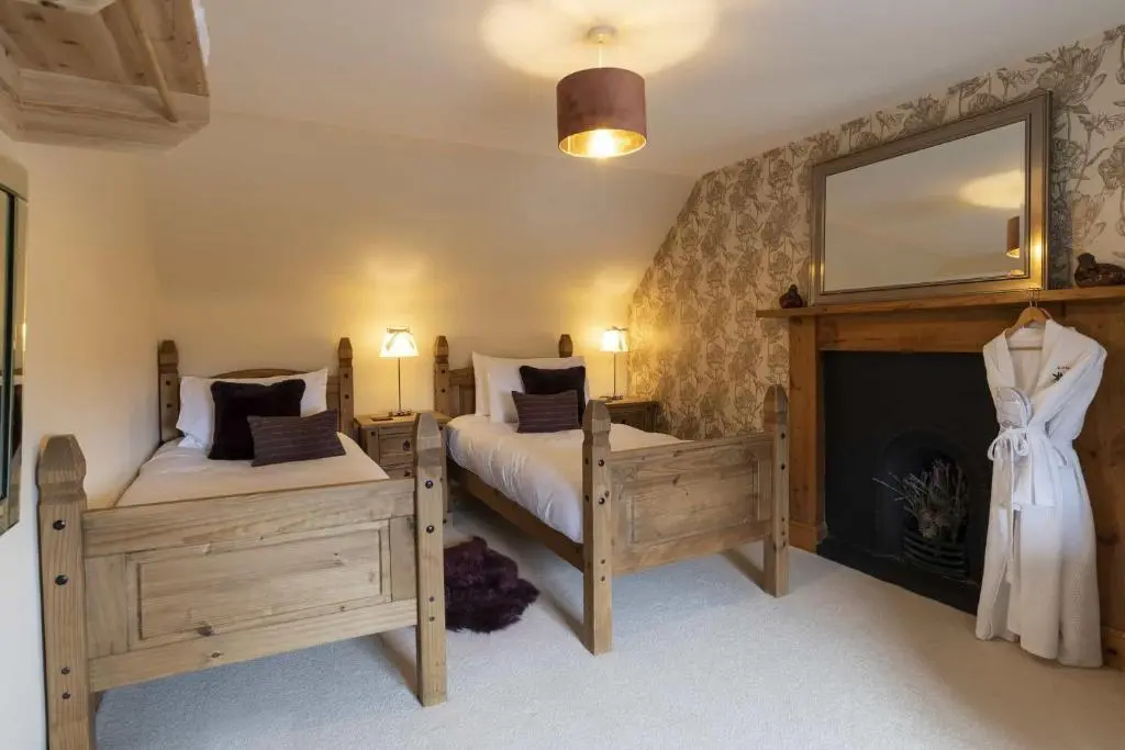 a bedroom with two twin beds and a fireplace at Rowan Cottage in Aviemore