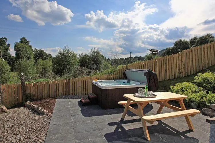 a backyard with a hot tub and a wooden fence at Rowan Cottage in Aviemore