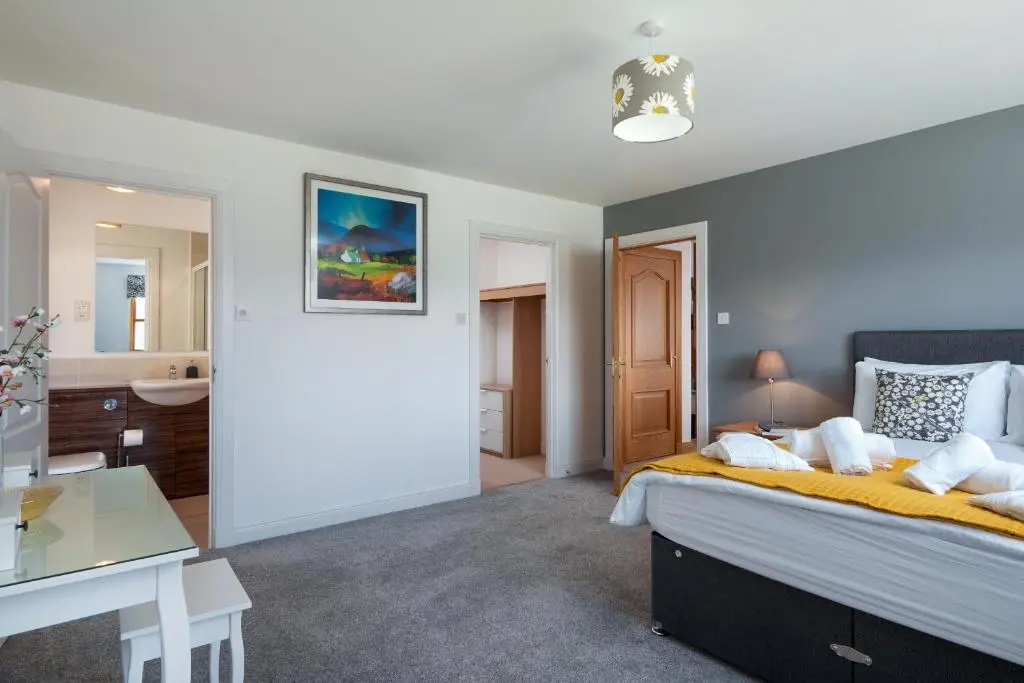 a bedroom with a large bed and a bathroom at Snowmass Lodge - hot tub in Aviemore in Aviemore