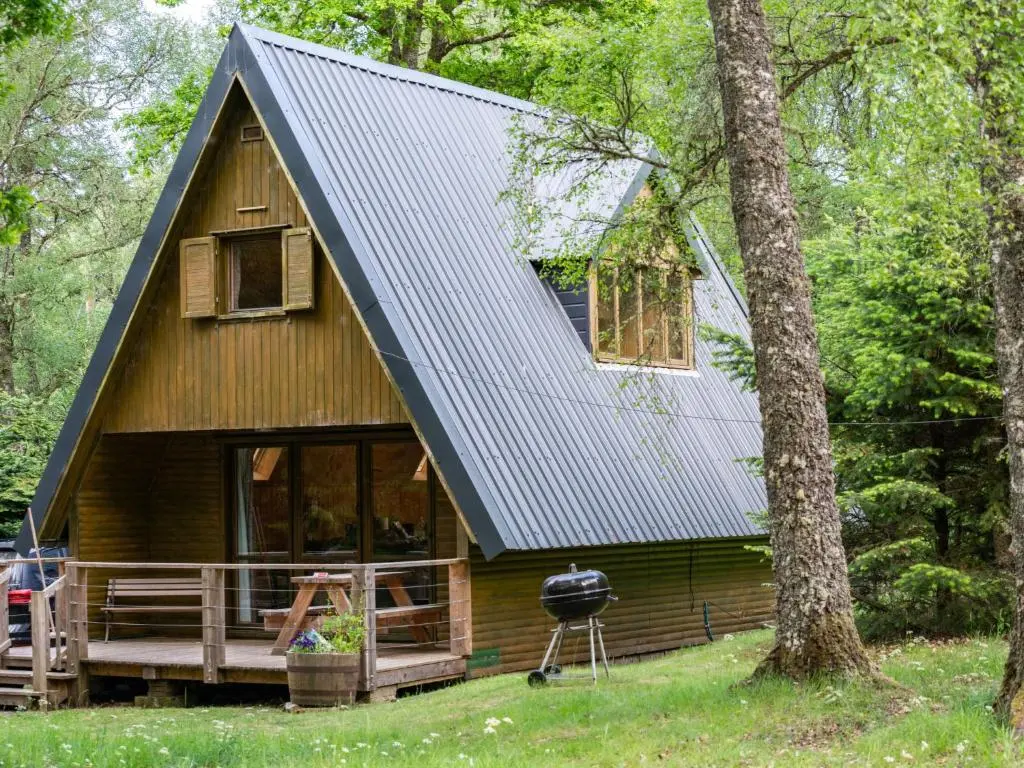 a cabin in the woods with a black roof at Chalet Birchwood Cottage by Interhome in Inverness