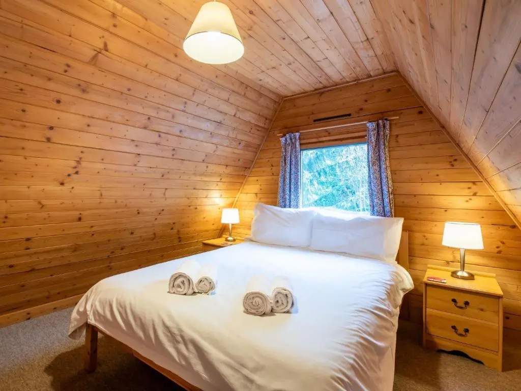 a bedroom with a bed in a log cabin at Chalet Rowan Cottage by Interhome in Inverness