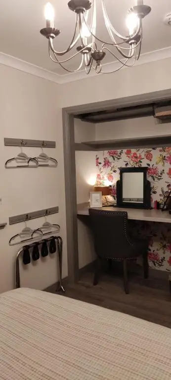 a bedroom with a bed and a desk with a television at Rooms at The Cooperage in Auchleven