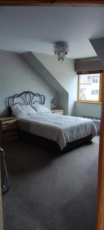 a bedroom with a large bed with a chandelier at Rooms at The Cooperage in Auchleven