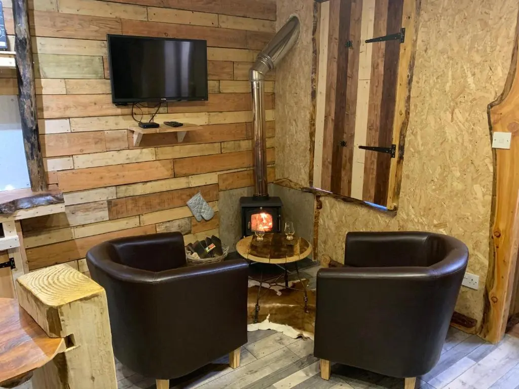 a living room with two chairs and a fireplace at The Bothy Aberlour in Aberlour