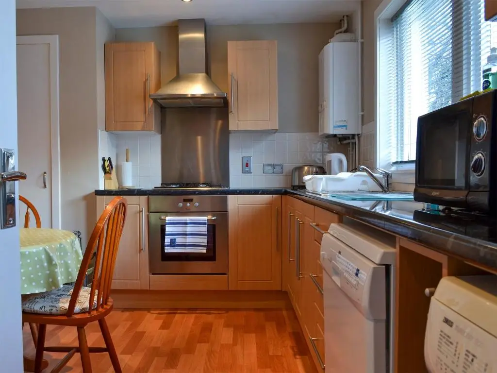 a kitchen with a stove top oven next to a table at Brae Lodge in Cullen