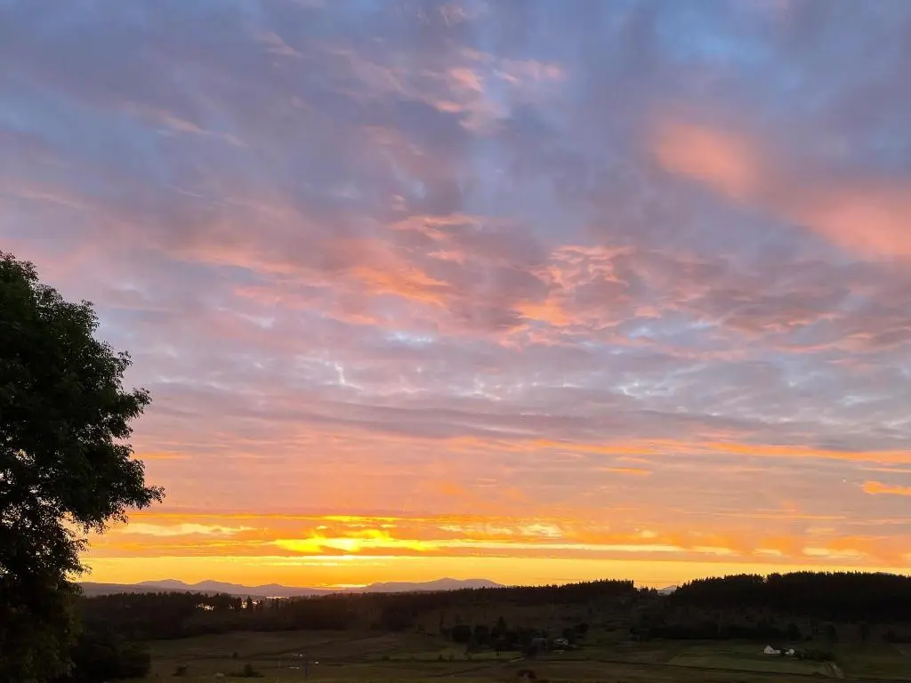a cloudy sky with the sun setting in a field at The Barn in Lairg