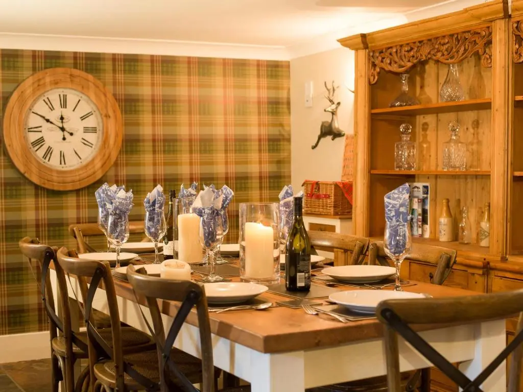 a dining room with a table and a clock on the wall at The Maltings - lodge with hot tub in Nethy Bridge