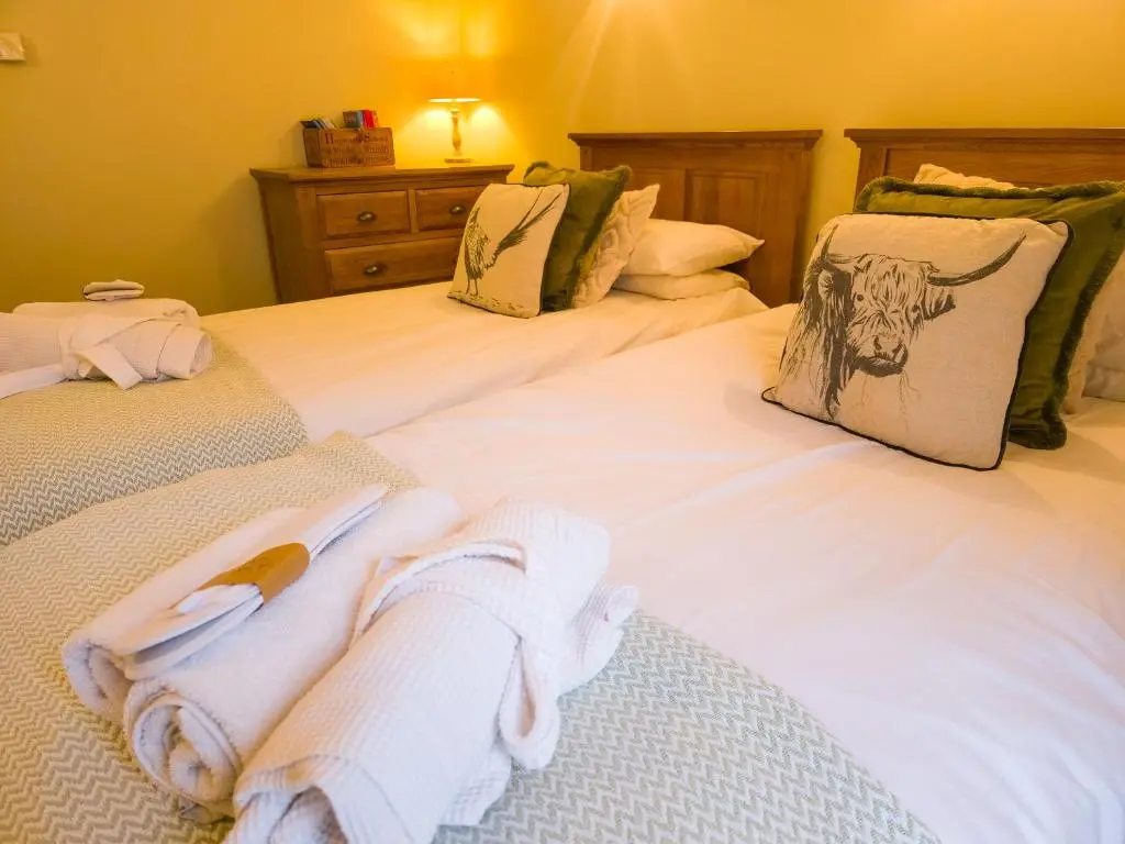 a bedroom with two beds with towels on them at The Maltings - lodge with hot tub in Nethy Bridge
