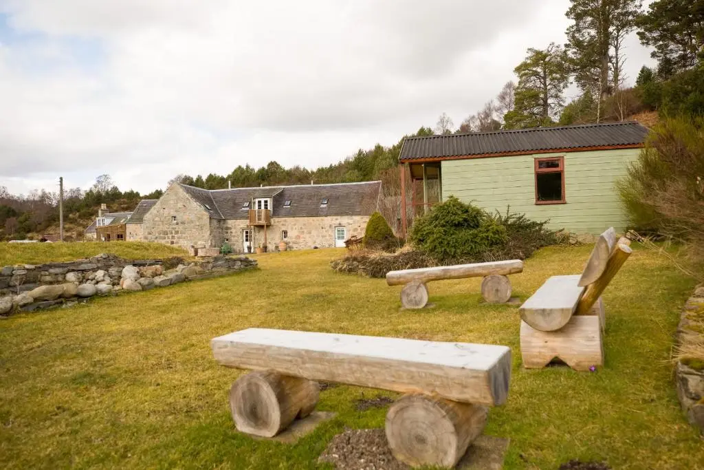 a yard with wooden benches in front of a building at The Maltings - lodge with hot tub in Nethy Bridge