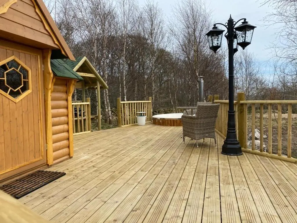 a wooden deck with a lamp and a house at Woodland Lodge Oxen Craig in Kintore