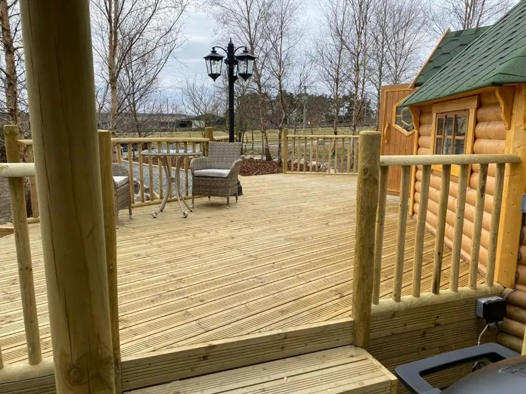 a wooden deck with a chair and a table at Woodland Lodge Oxen Craig in Kintore