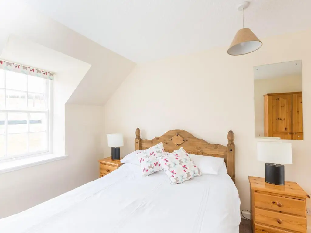 a bedroom with a white bed with two pillows at Balnain 1 in Cononbridge