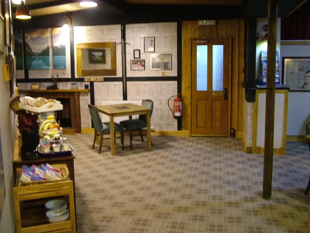 a room with a table and chairs and a door at The Steading Highland Glen Lodge in Drumnadrochit