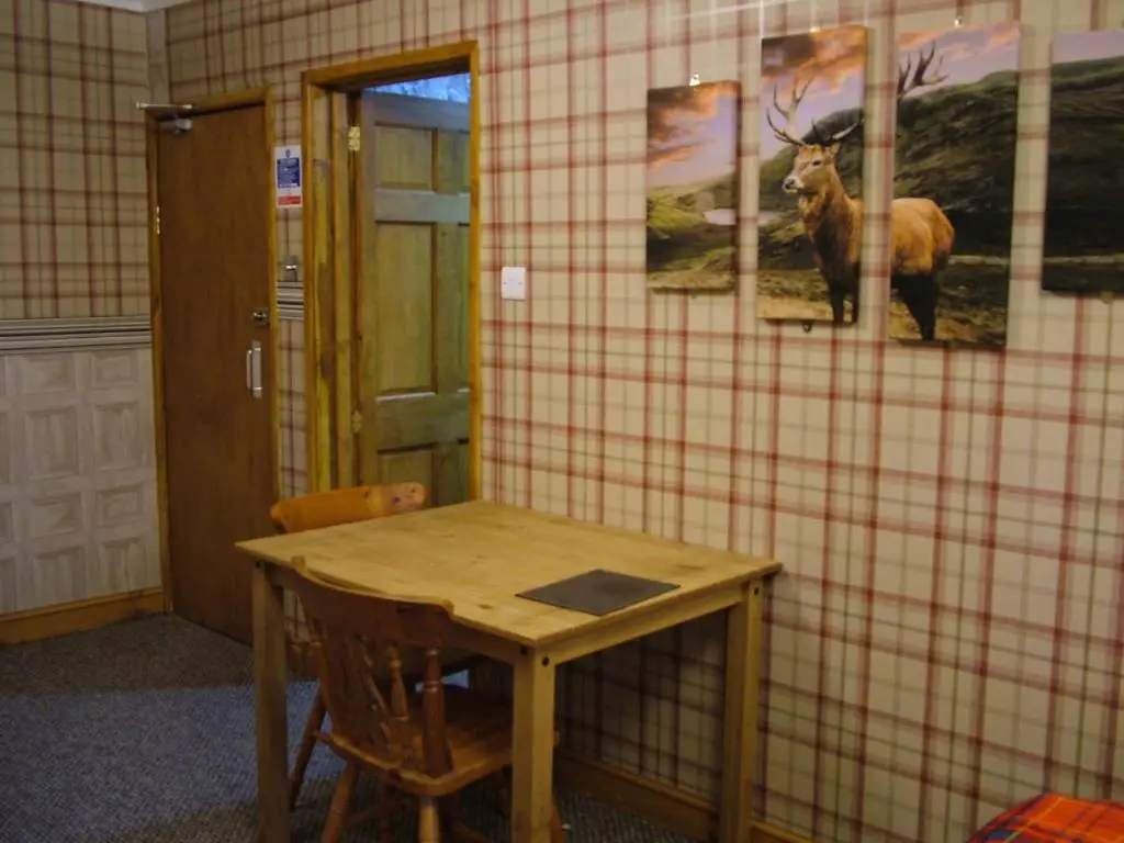 a room with a table and a picture of a deer on the wall at The Steading Highland Glen Lodge in Drumnadrochit