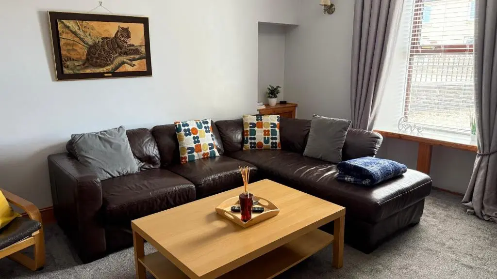 a living room with a brown leather couch and a coffee table at Newly Refurbished 2 Bedroom flat on NC500 route in Wick