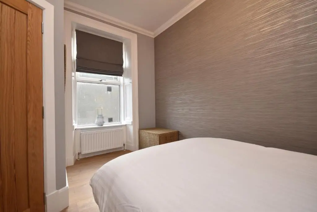 a bedroom with a white bed and a window at Signature Apartments in Fraserburgh