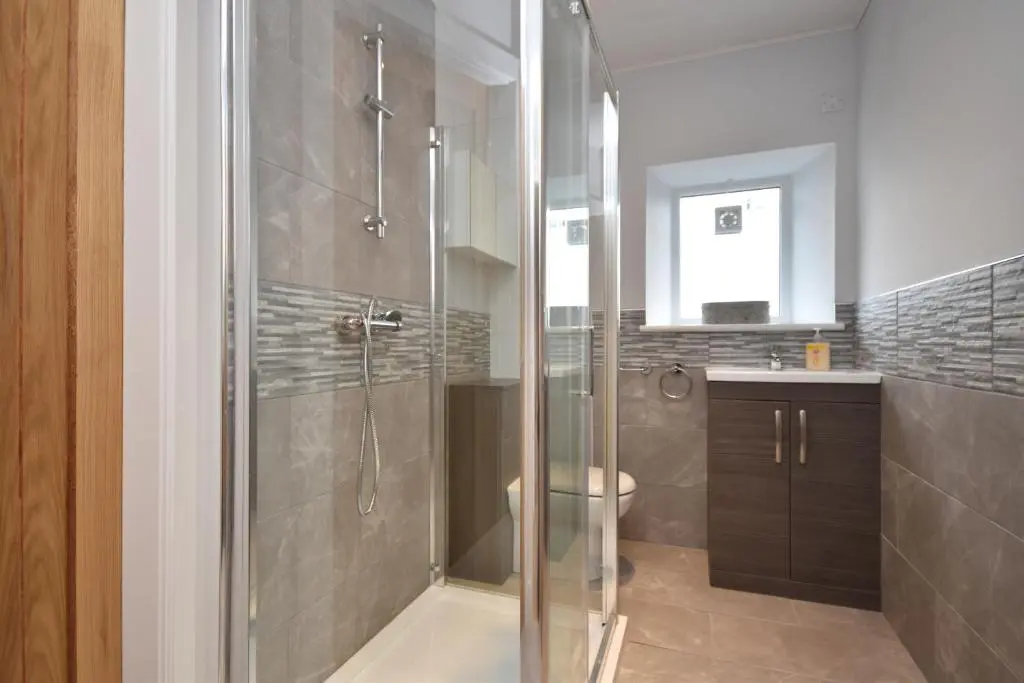 a bathroom with a shower with a toilet and a sink at Signature Apartments in Fraserburgh