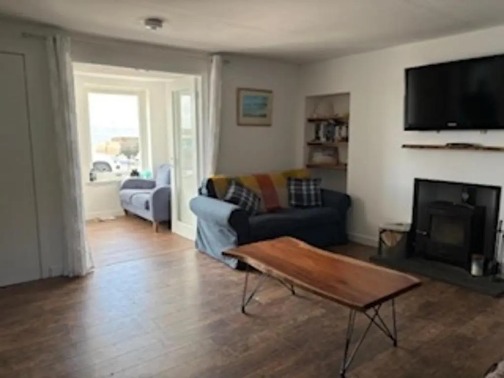 a living room with a couch and a tv at PetFriendly-Beachfront-SunsetFacingSunPorch-Garden in Portmahomack