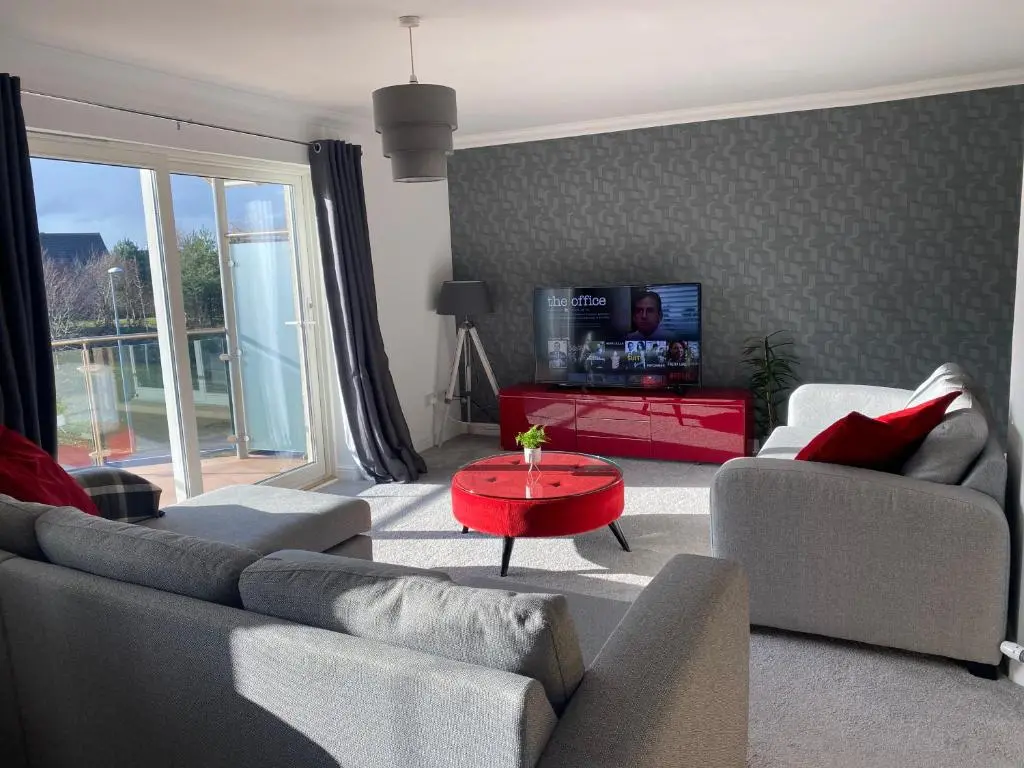 a living room with two couches and a red table at The Duplex Nairn- Spacious 3 Bedroom with sunny balcony in Nairn