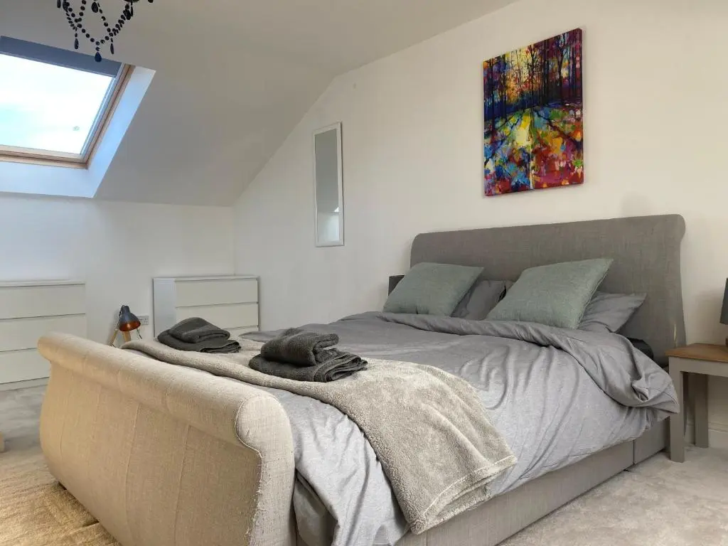 a bedroom with a bed and a painting on the wall at The Duplex Nairn- Spacious 3 Bedroom with sunny balcony in Nairn