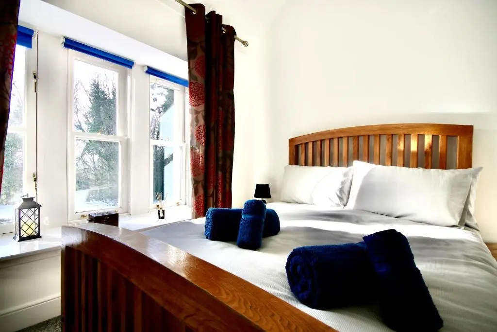 a bedroom with a large bed with blue pillows on it at Serviced Accommodation Moray - Lesmurdie House in Elgin