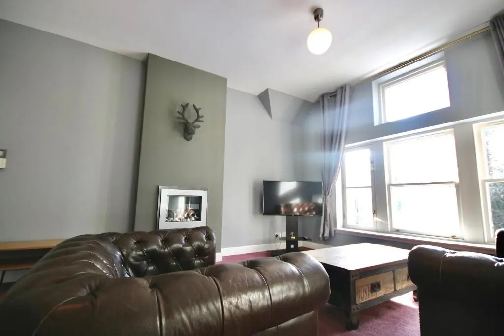 a living room with a leather couch and a table at Serviced Accommodation Moray - Lesmurdie House in Elgin