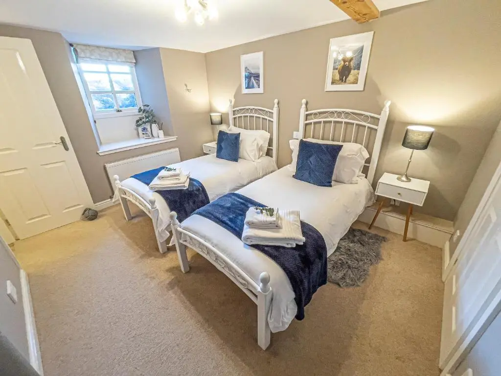 a bedroom with two beds with blue pillows at The Barley Mill in Elgin
