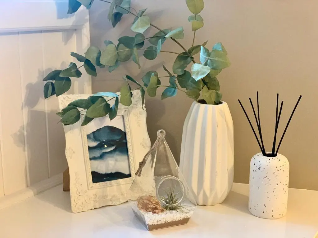 a table with two vases and a picture and plants at The Barley Mill in Elgin
