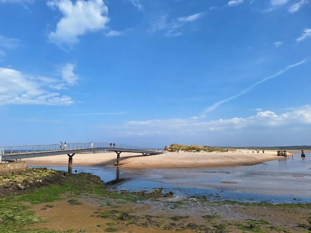 a bridge over a beach with people walking on it at 1 Fulmar Road**Next to West Beach and Golf Course in Lossiemouth