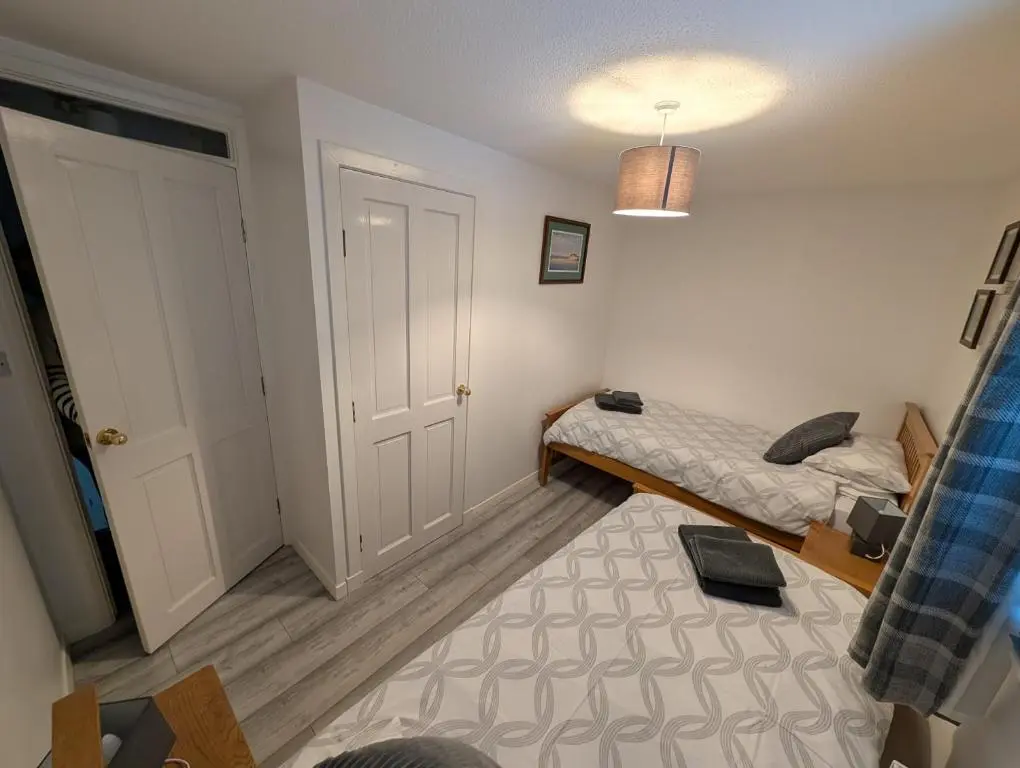 a small bedroom with a bed and a door at 1 Fulmar Road**Next to West Beach and Golf Course in Lossiemouth