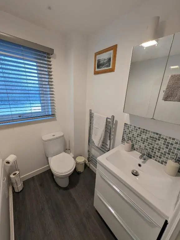 a white bathroom with a toilet and a sink at 1 Fulmar Road**Next to West Beach and Golf Course in Lossiemouth