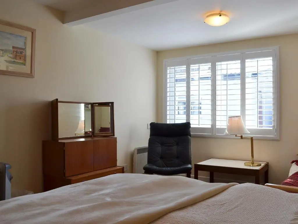 a bedroom with a bed and a chair and a window at Bruich Cottage in Newtonmore