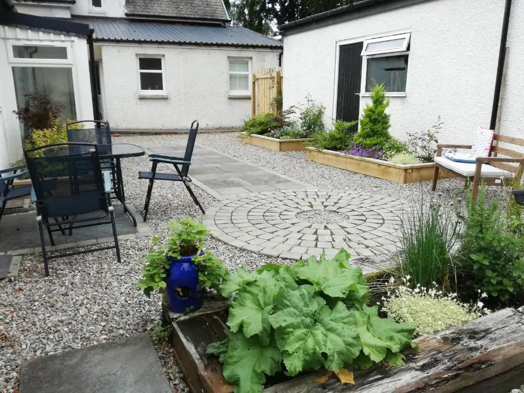 a garden with a patio with a table and some lettuces at Bruich Cottage in Newtonmore