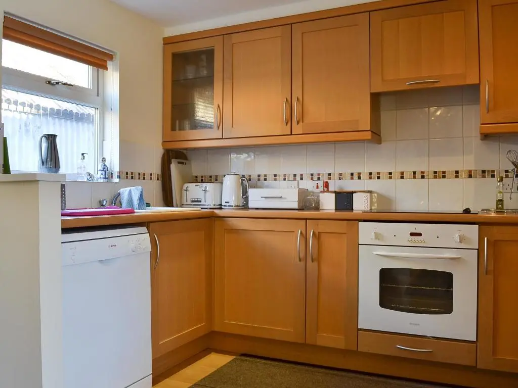 a kitchen with wooden cabinets and white appliances at Bruich Cottage in Newtonmore