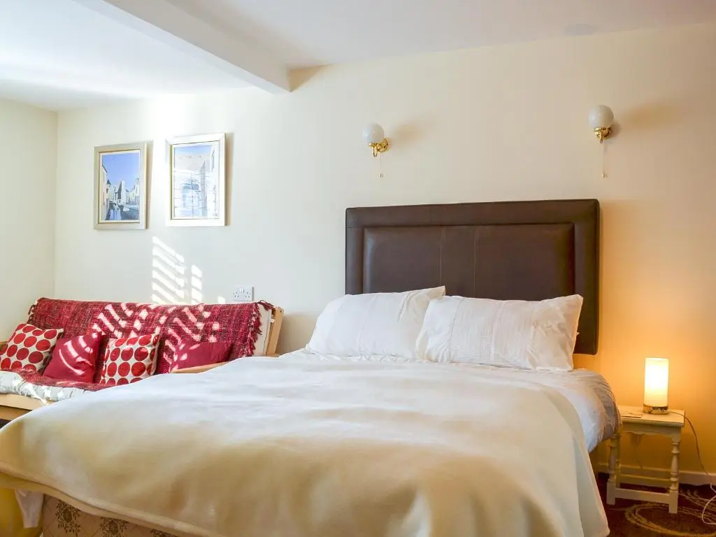 a bedroom with a large white bed with red pillows at Bruich Cottage in Newtonmore