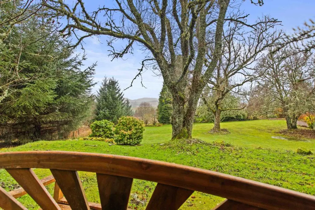 a wooden bench with a view of a park at Freuchies Mill - A Holiday Home For All Seasons. in Blairgowrie